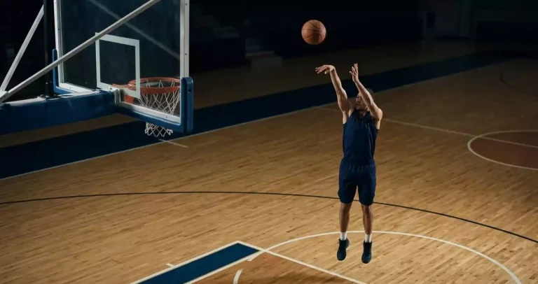 NBA shooting guard releasing a mid-range jump shot on a hardwood court during an indoor game